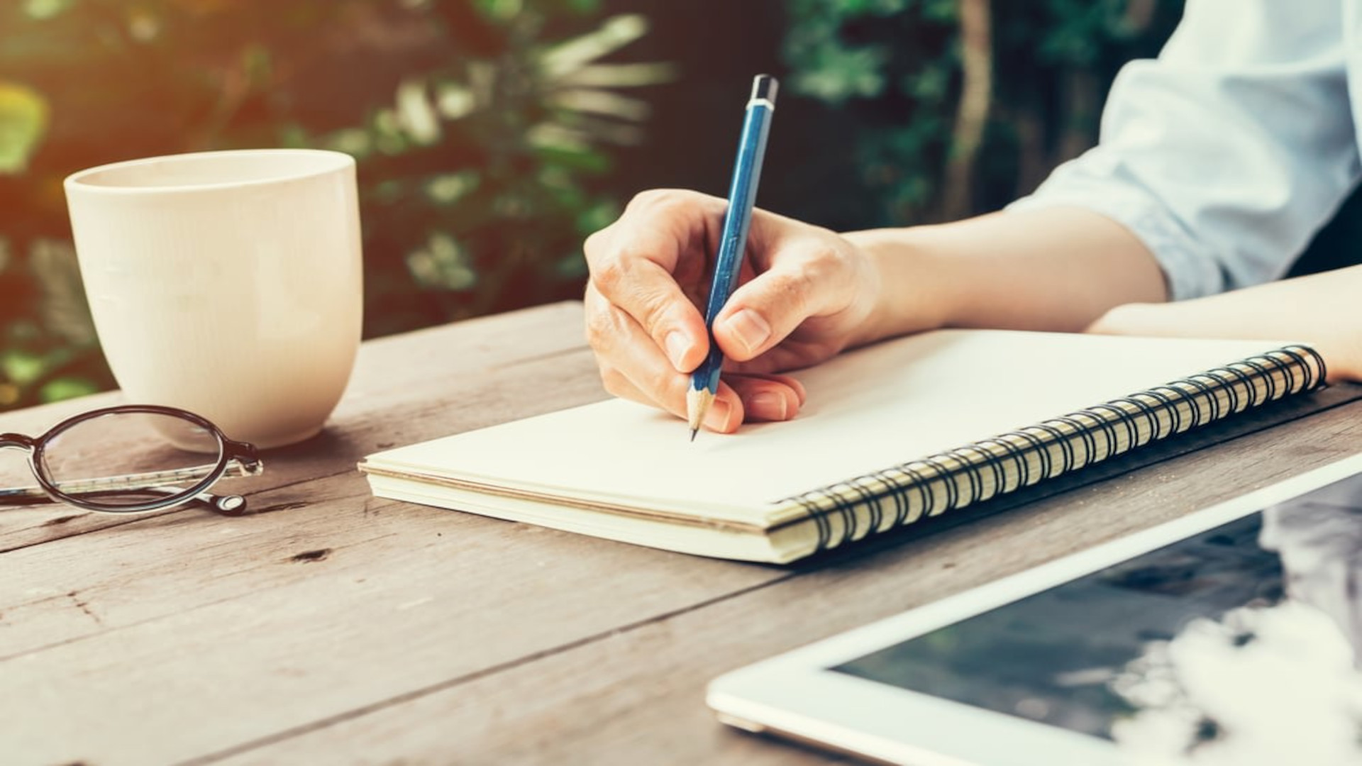 Person sitting at a wooden table writing in a notebook