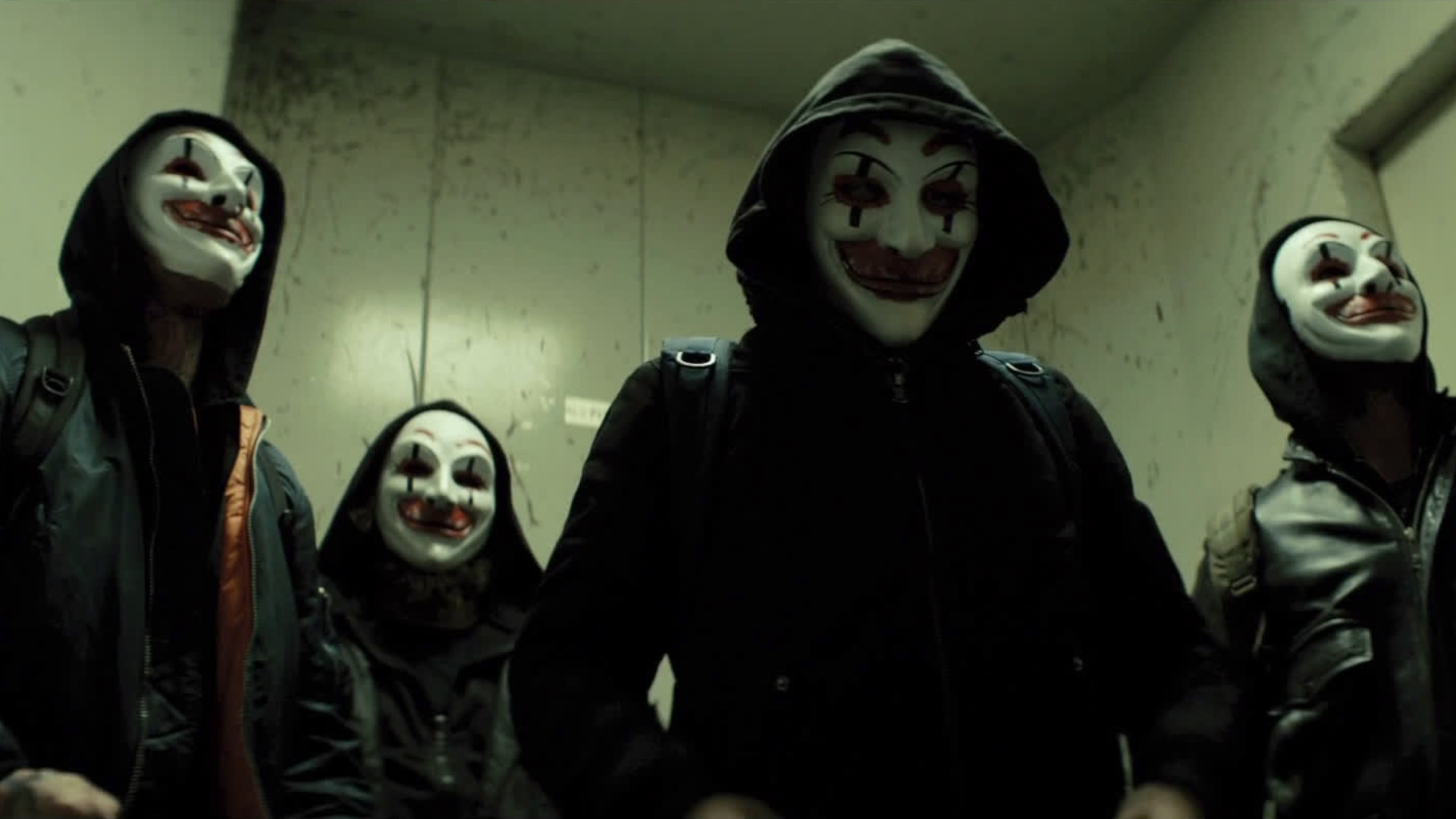 Four hooded figures wearing clown masks